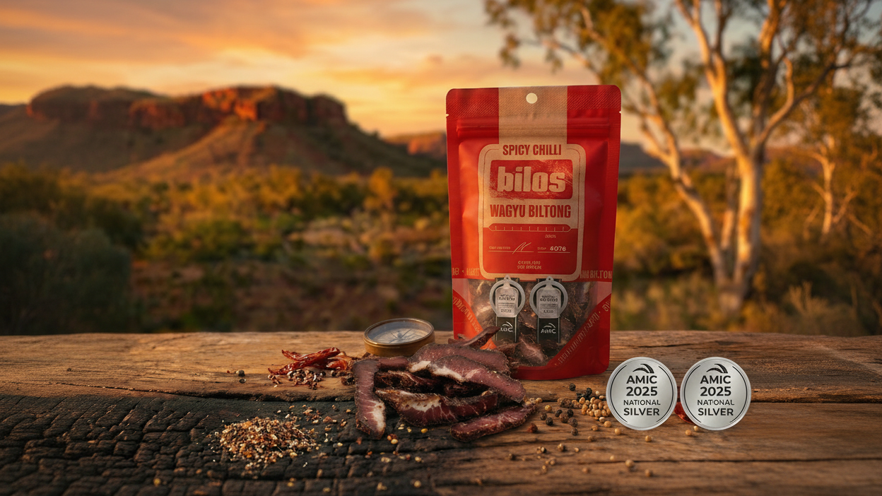 Red package of 'Bilo's Wagy Mildura' spicy chilli on a wooden surface with a scenic background.